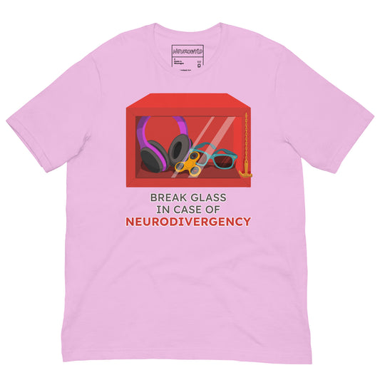 pink t-shirt featuring a red emergency box illustration filled with noise-canceling headphones, a fidget spinner, sunglasses, and a small anchor. Below the box, bold text reads 'Break Glass in Case of Neurodivergency' with 'Neurodivergency' highlighted in red.