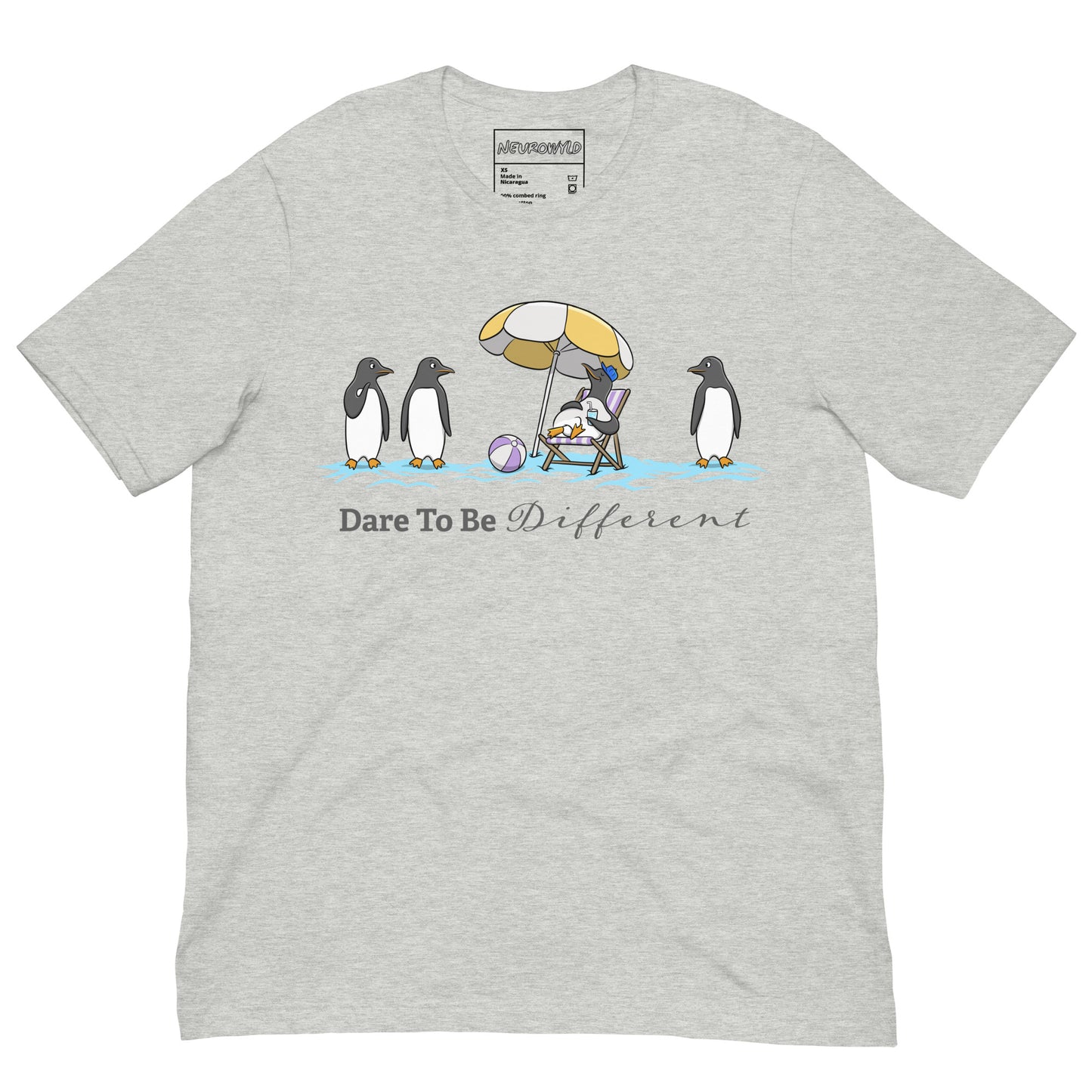 Light gray t-shirt featuring three penguins standing in a row while a fourth penguin lounges under a beach umbrella with a drink, surrounded by sand and a beach ball. Below the illustration, the text reads 'Dare To Be Different' in bold and script font.