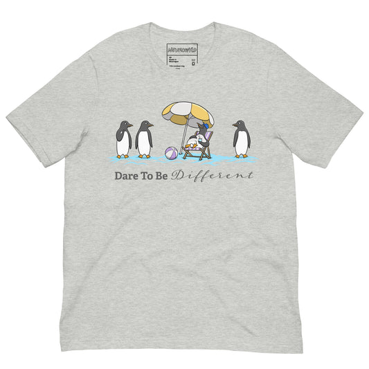 Light gray t-shirt featuring three penguins standing in a row while a fourth penguin lounges under a beach umbrella with a drink, surrounded by sand and a beach ball. Below the illustration, the text reads 'Dare To Be Different' in bold and script font.
