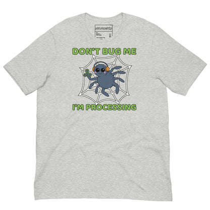 Light gray t-shirt featuring a cartoon spider sitting in a web, wearing orange headphones and holding a green fidget spinner. Above the spider, bold green text reads 'Don't Bug Me,' and below it says 'I'm Processing'.