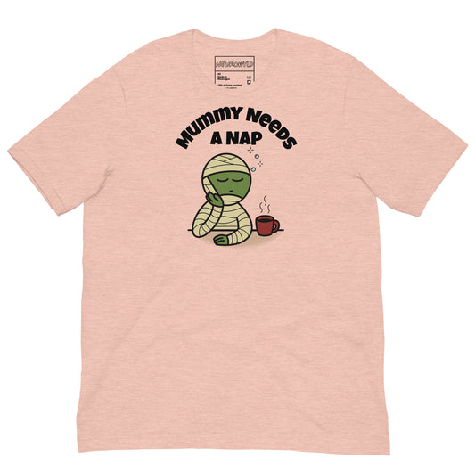 Light pink t-shirt featuring a sleepy green mummy resting its head on one hand beside a steaming coffee cup. Above, the text reads 'Mummy Needs A Nap' in bold black letters.