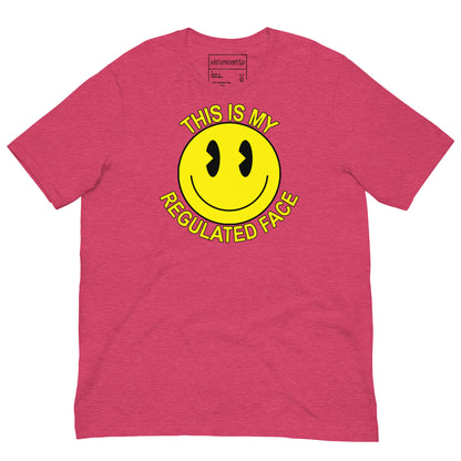 Pink t-shirt with a large yellow smiley face graphic. Text above and below the face reads ‘This Is My Regulated Face,’ combining humor and neurodivergent pride.