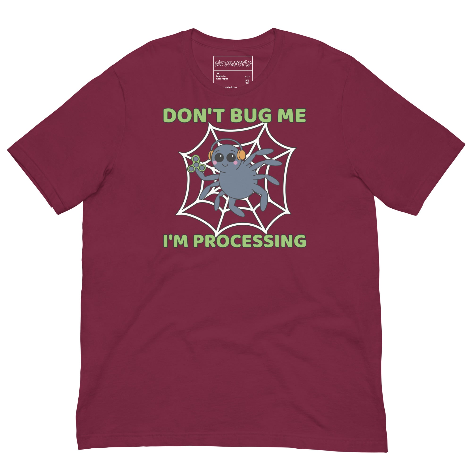 maroon t-shirt featuring a cartoon spider sitting in a web, wearing orange headphones and holding a green fidget spinner. Above the spider, bold green text reads 'Don't Bug Me,' and below it says 'I'm Processing'.