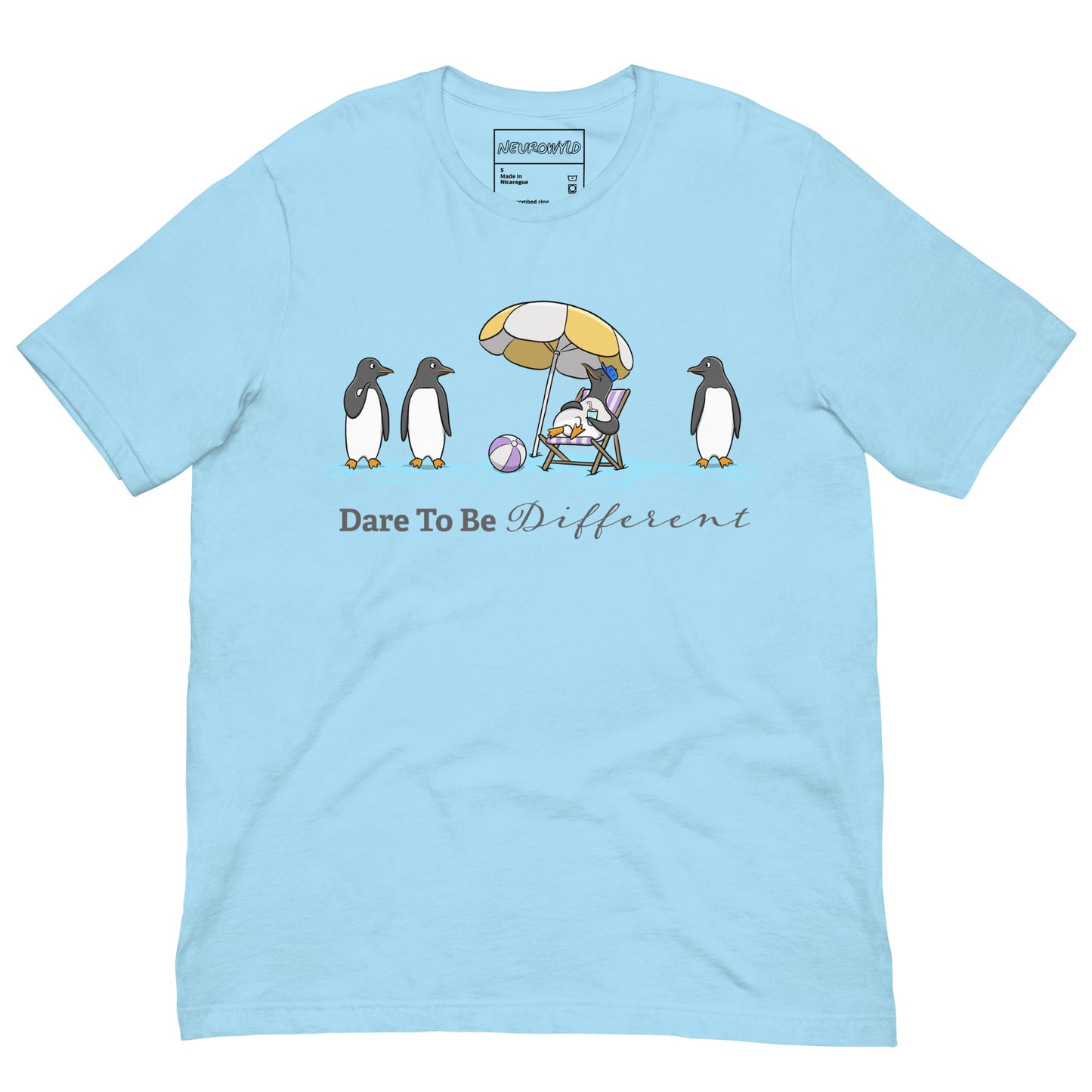 light blue t-shirt featuring three penguins standing in a row while a fourth penguin lounges under a beach umbrella with a drink, surrounded by sand and a beach ball. Below the illustration, the text reads 'Dare To Be Different' in bold and script font.
