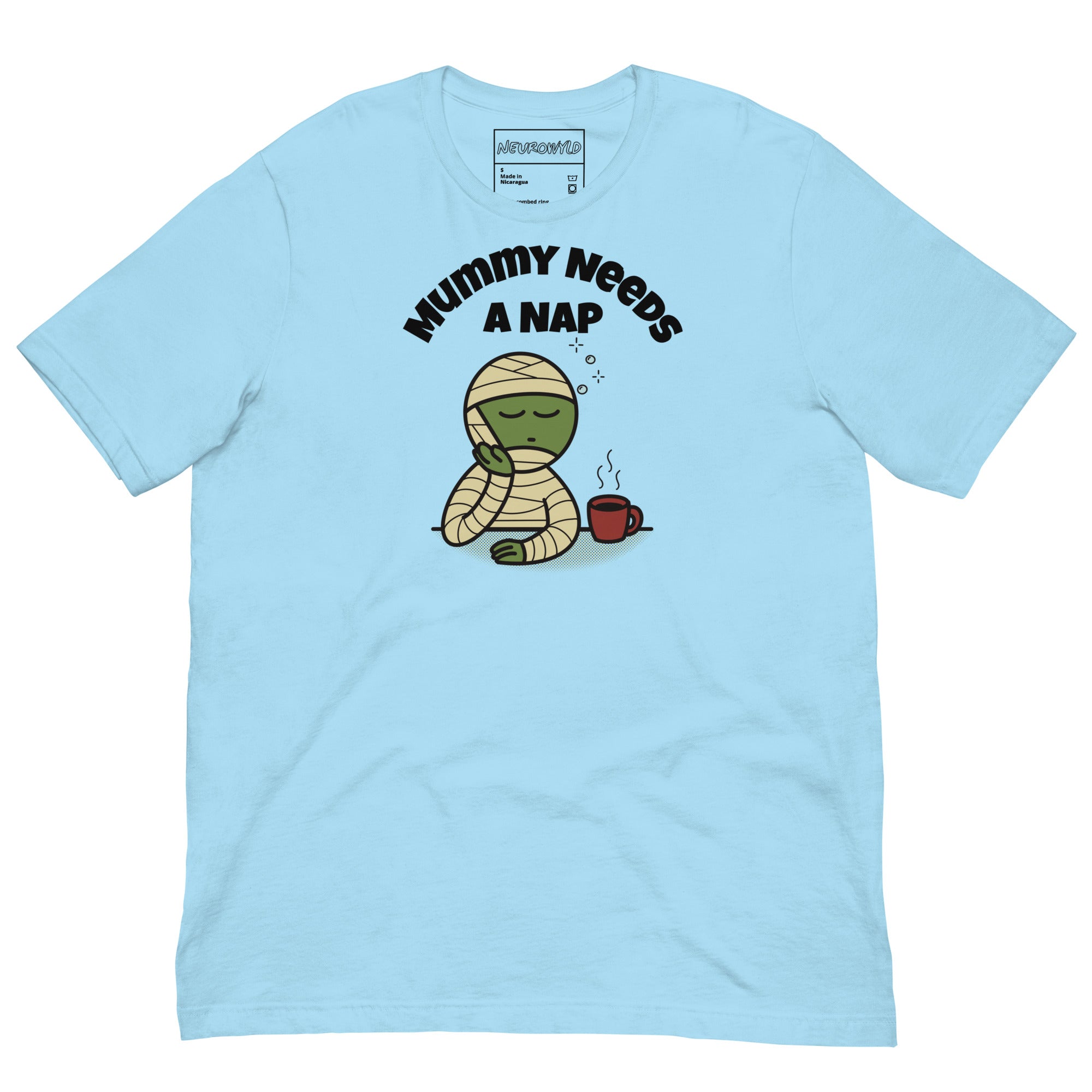 Light blue t-shirt featuring a sleepy green mummy resting its head on one hand beside a steaming coffee cup. Above, the text reads 'Mummy Needs A Nap' in bold black letters.
