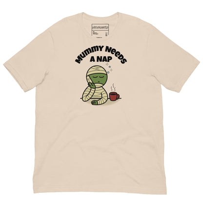 soft cream t-shirt featuring a sleepy green mummy resting its head on one hand beside a steaming coffee cup. Above, the text reads 'Mummy Needs A Nap' in bold black letters.